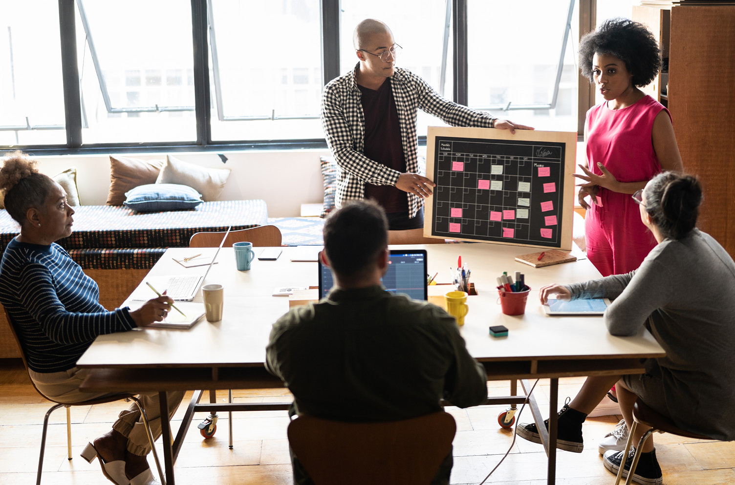 Organizational Change Strategies – Five people meet around a table while discussing a calendar.