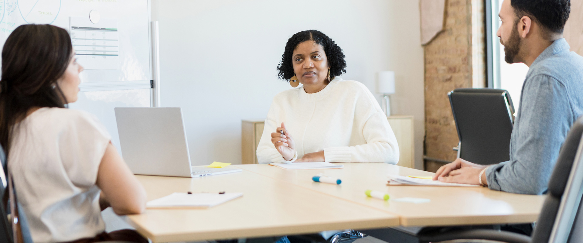 The mature adult manager listens to her employees during a meeting.