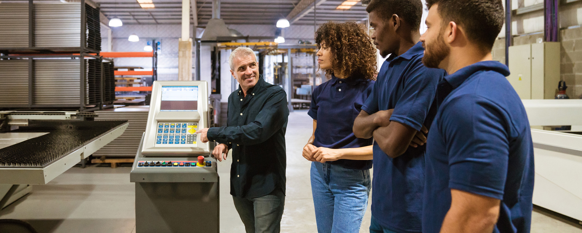 A supervisor training his three employees on how to operate a machine.