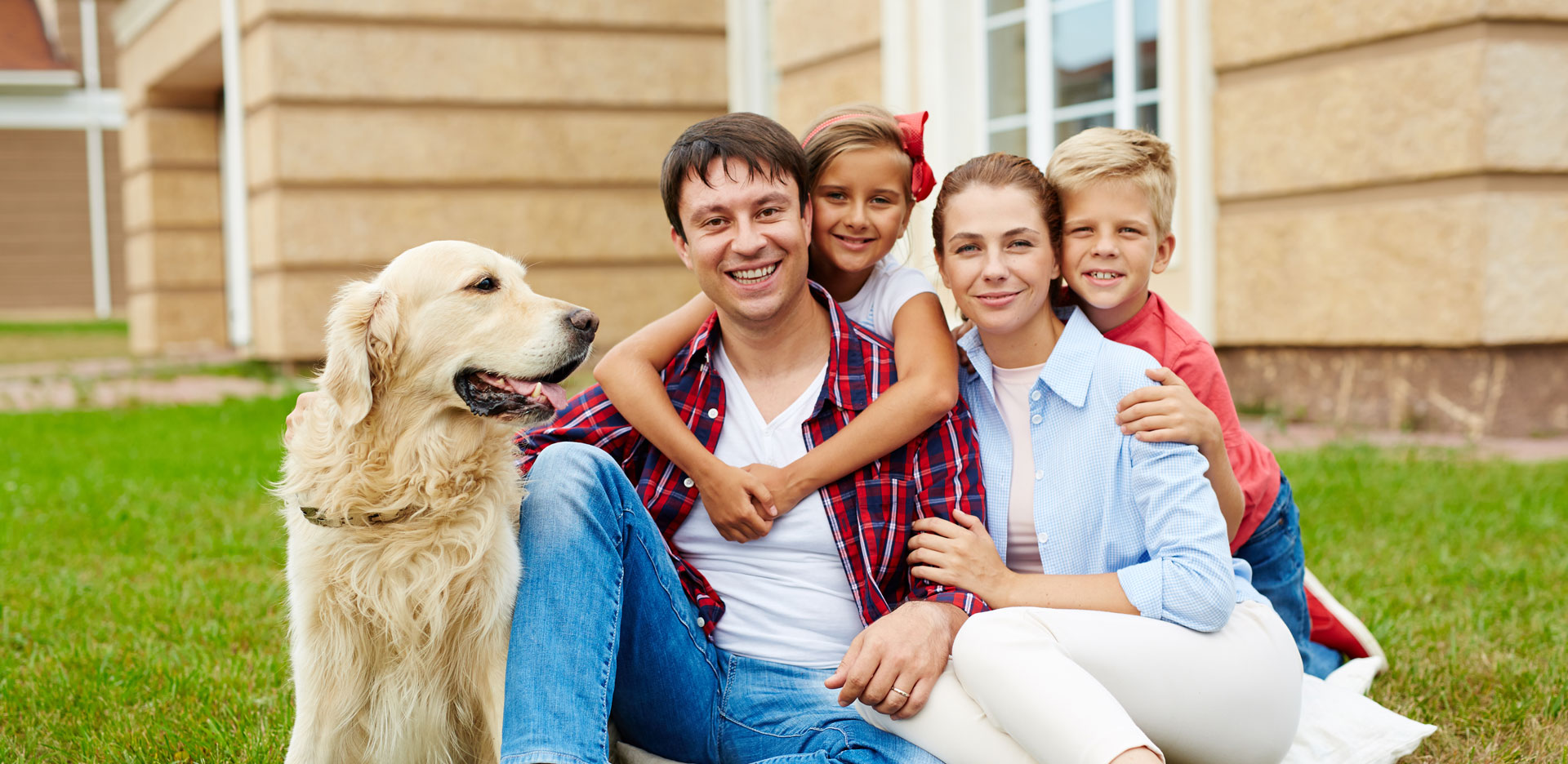 Mother and father sitting with their daughter, son, and a dog in their yard.
