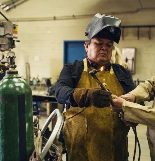 Middle-aged man learning to weld with his instructor.