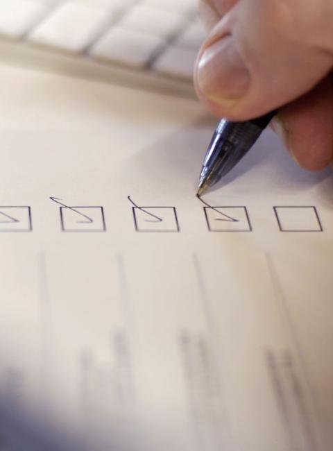 A hand checking boxes on a checklist.