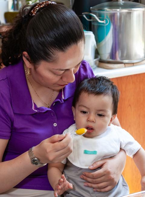 Mother feeding her baby in the dining room.