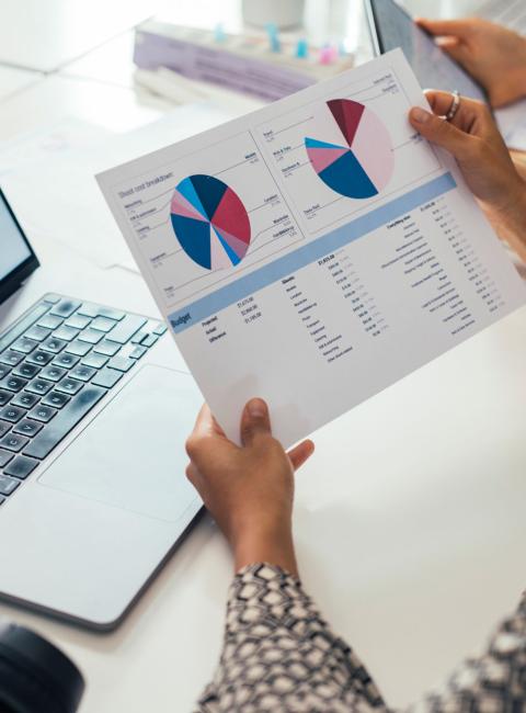 Woman holding paper documents containing graphs and financial data.